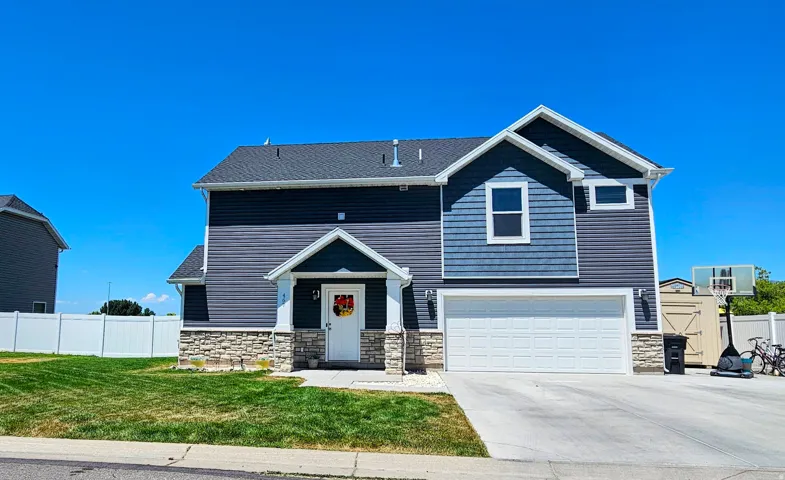 Two-story residence featuring dark blue horizontal siding, blue shingle siding, and stone veneer accents
