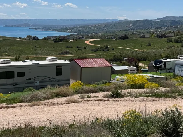 Expansive rural setting featuring a distant lake, rolling hills, and a backdrop of mountains
