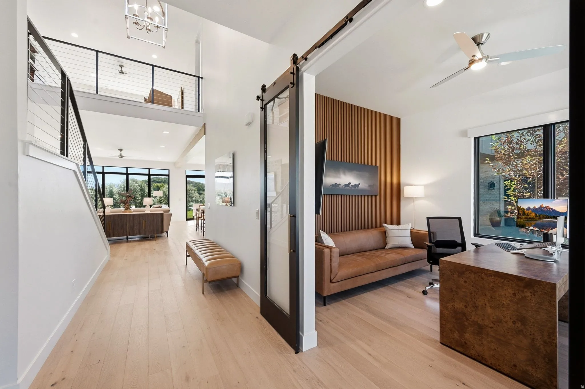 Hardwood-finish flooring extending through an open-concept layout with high ceilings and a second-level overlook featuring cable railings