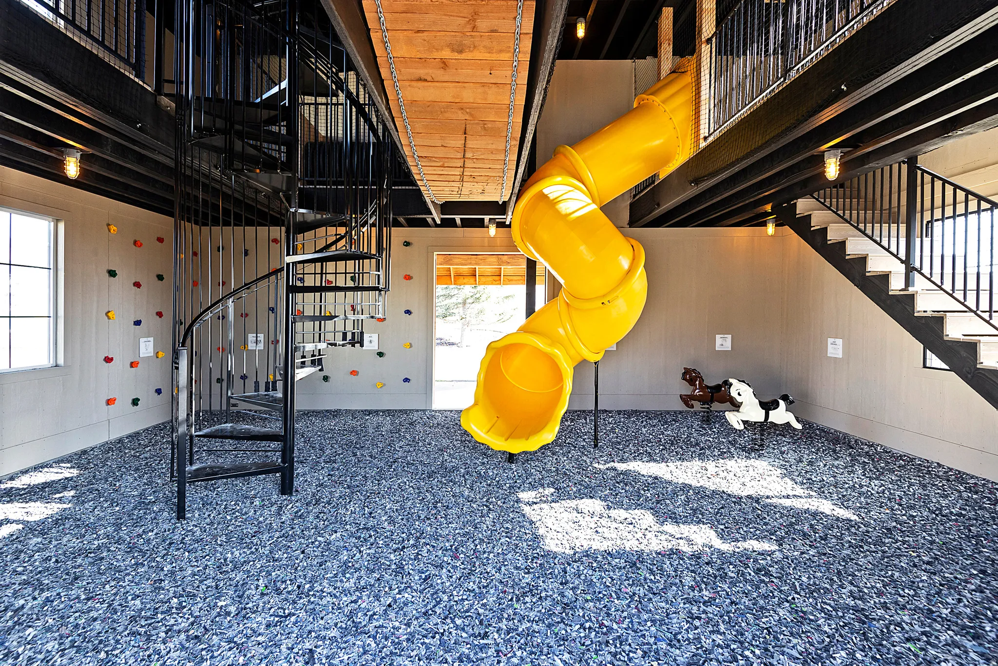 Recreational room featuring a spiral staircase, climbing wall, and a yellow tube slide