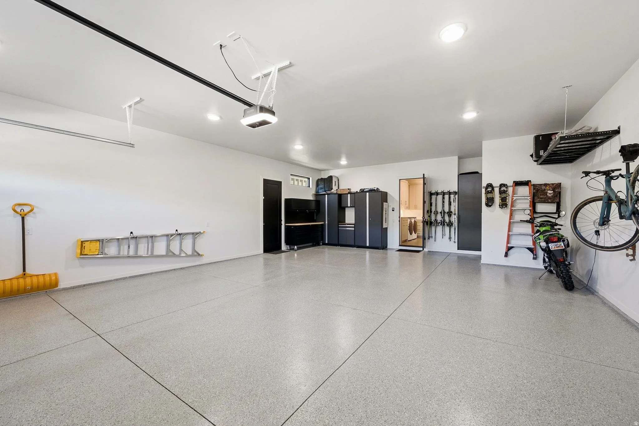 Spacious garage featuring a light-toned epoxy floor, recessed lighting, and built-in cabinetry with dark finishes