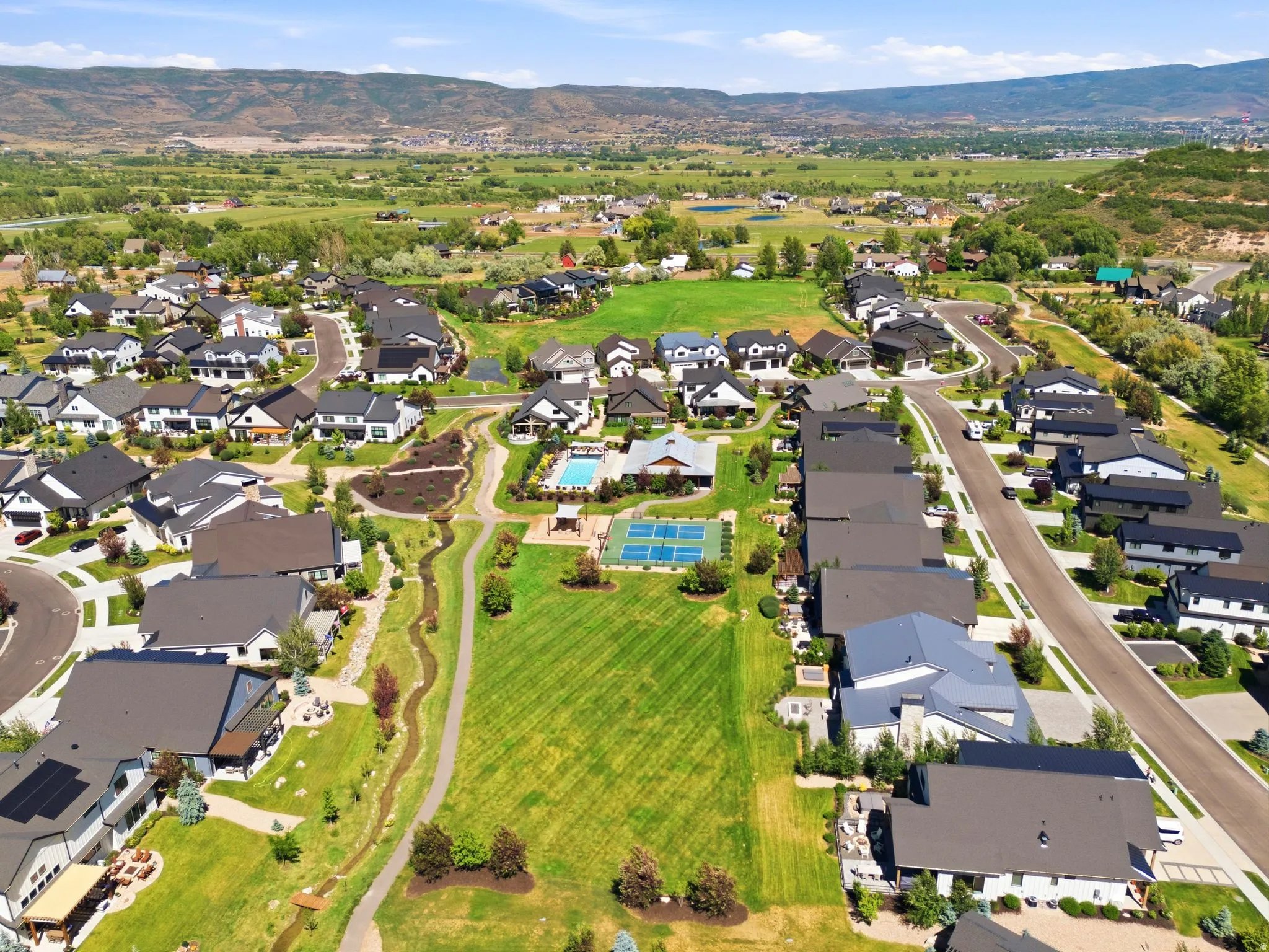 Aerial representation of a residential community featuring diverse architectural styles, an outdoor swimming pool, and multiple tennis courts