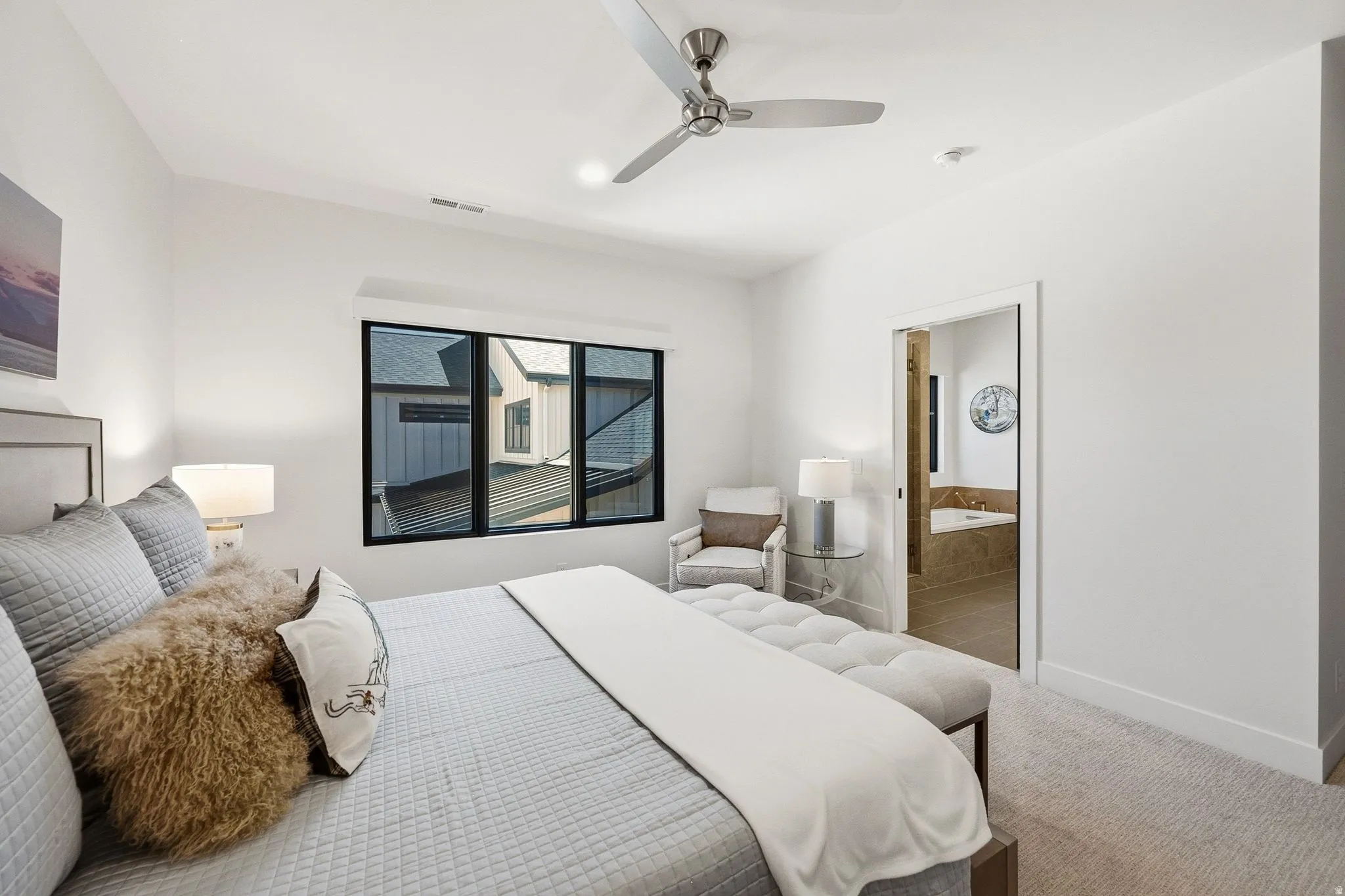 Bright room featuring a modern ceiling fan, large window with dark trim, and carpeted flooring