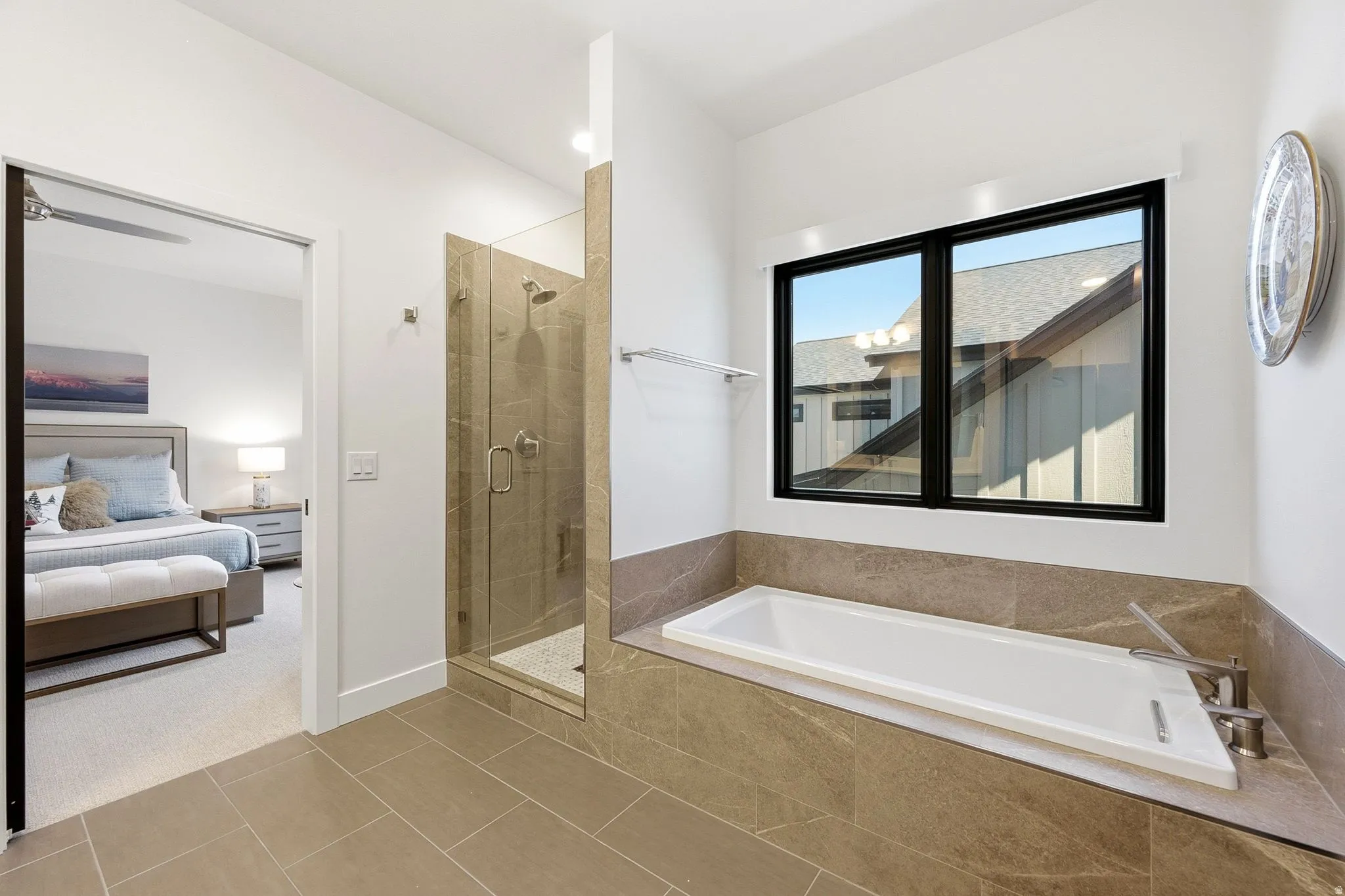 Spacious bathroom featuring a built-in soaking tub, large window, and a glass-enclosed shower
