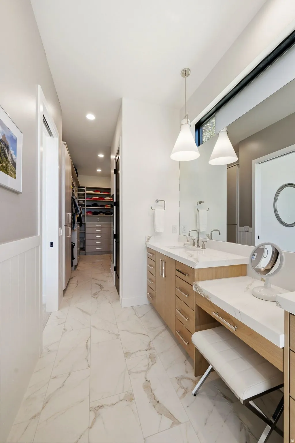 Bathroom vanity area featuring dual sinks, a built-in dressing table, and pendant lighting