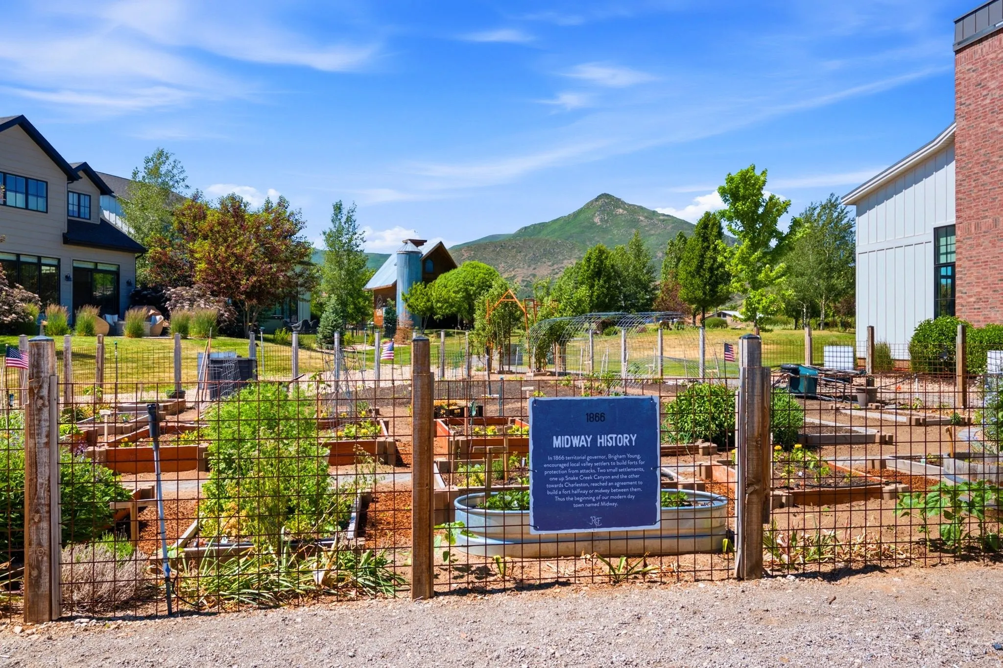 Community garden plots framed by a rustic wire fence and wood posts