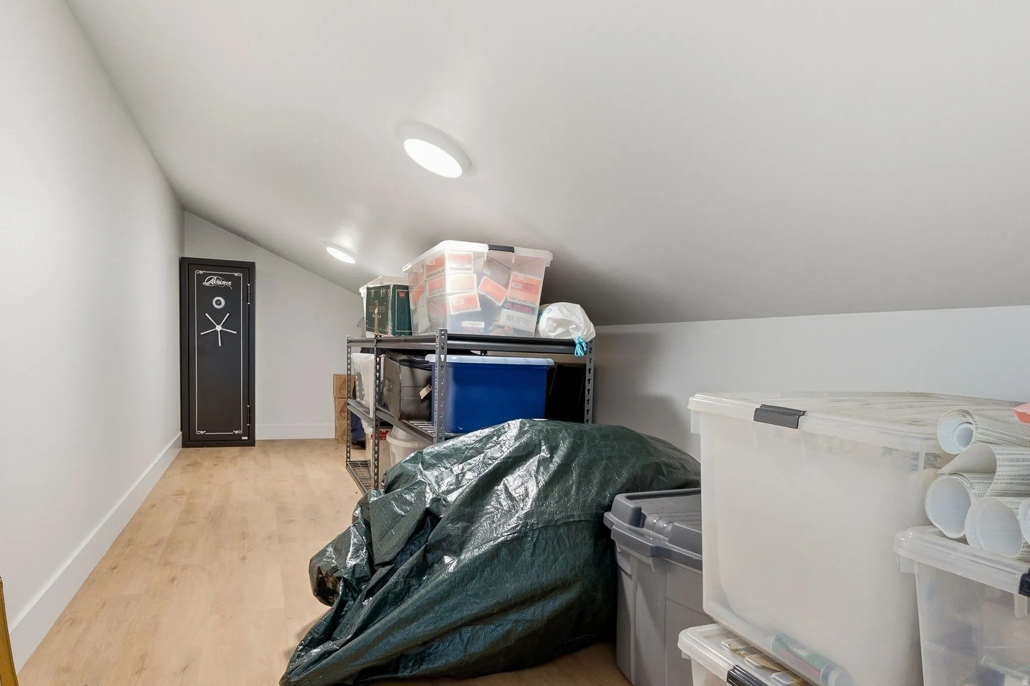Attic storage space featuring wood-finish flooring, white walls, and recessed ceiling lighting
