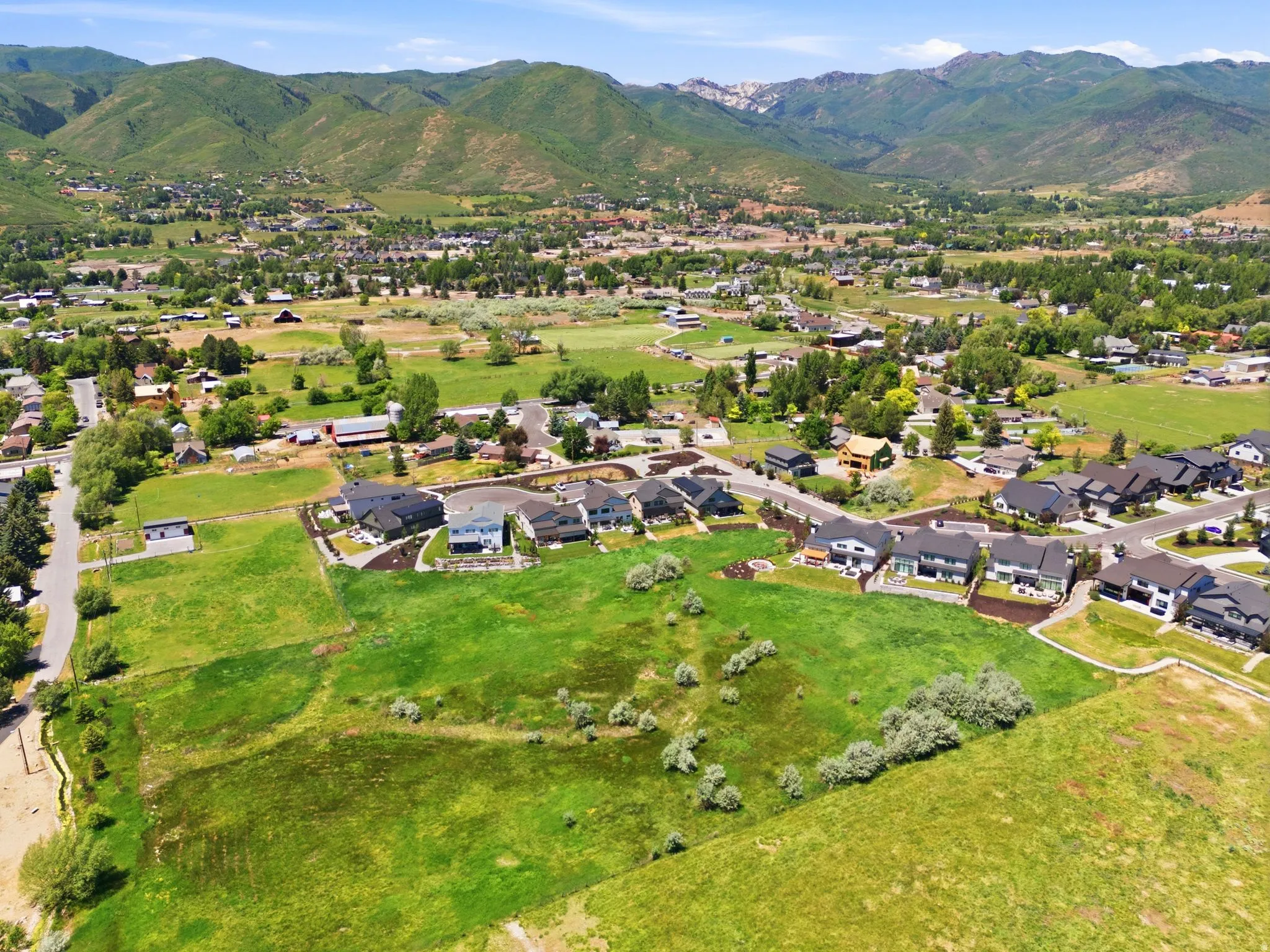 Expansive green space with distant mountain ranges, bordered by a residential community and paved roads