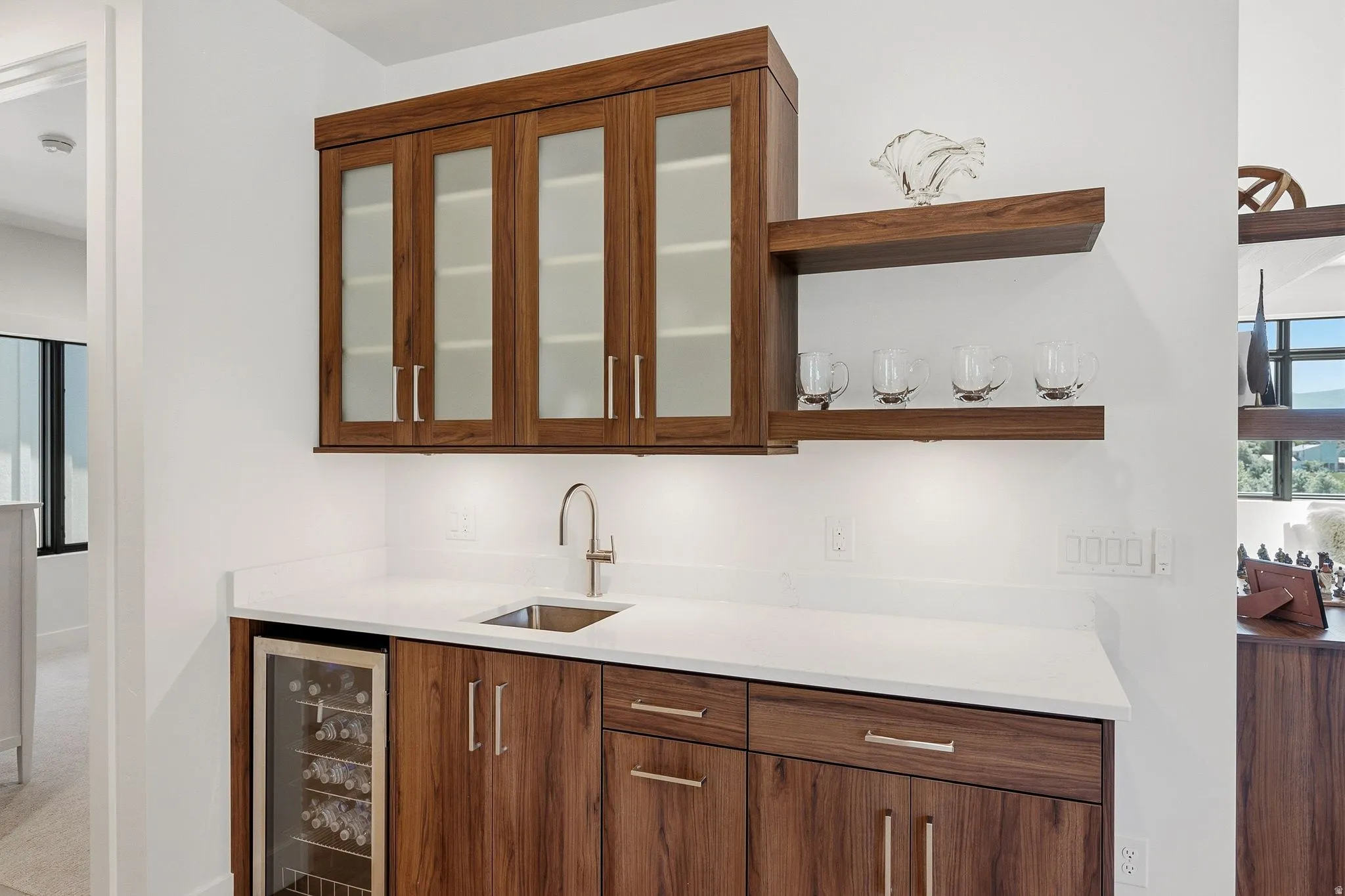 Integrated wet bar featuring rich wood-finish cabinetry, a stainless steel sink, and a built-in beverage cooler
