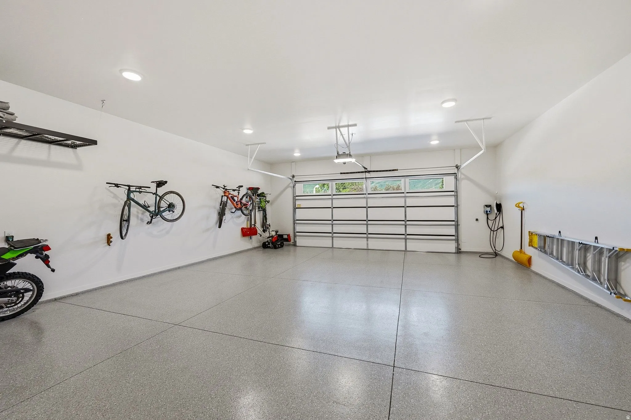 Spacious garage featuring a durable epoxy floor, recessed lighting, white walls, and an overhead door with window panels