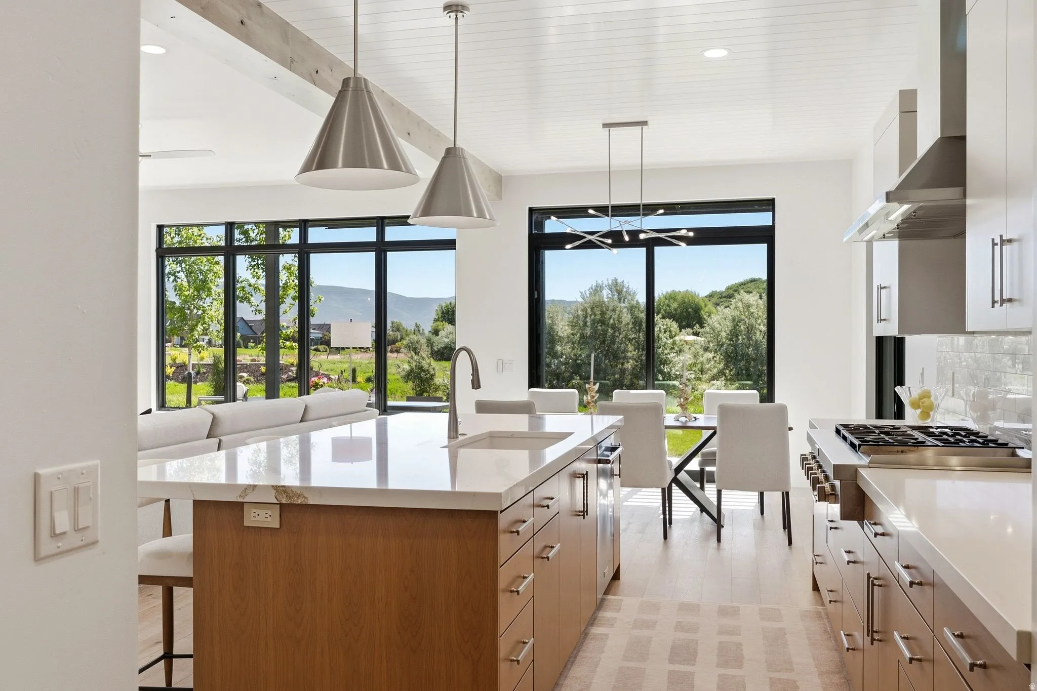 Open-concept kitchen and dining area featuring a spacious island with a light-toned countertop, wood-finish cabinetry, and stainless steel appliances