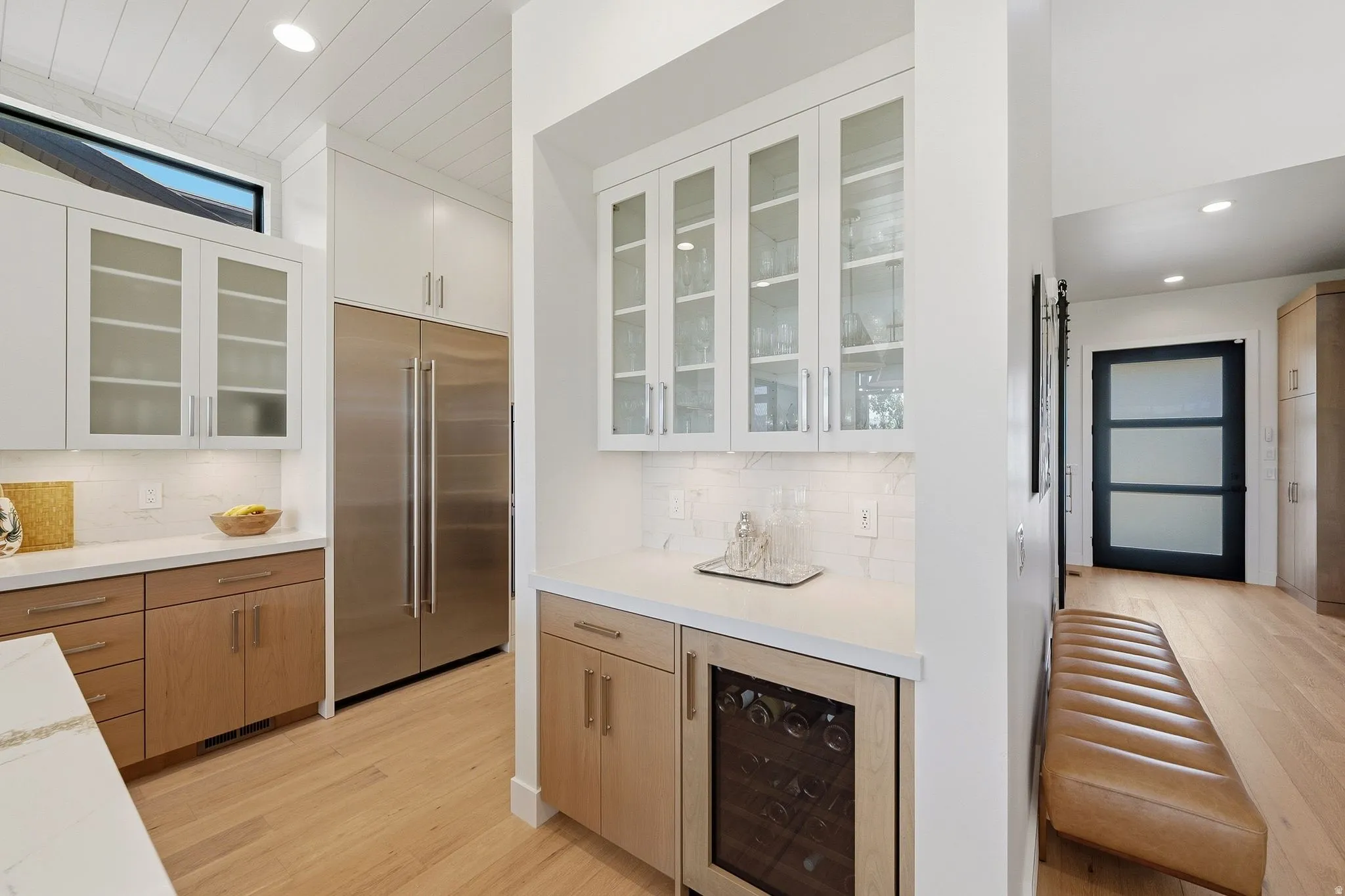 Modern kitchen featuring wood-finish flooring, white countertops, and a white subway tile backsplash