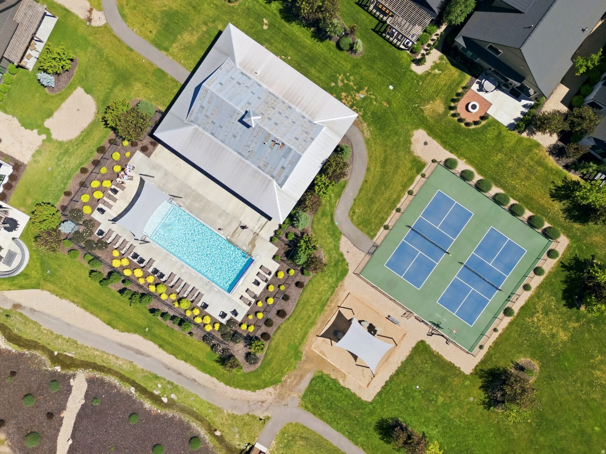 Outdoor amenities featuring a swimming pool, two pickleball courts, and a shaded play area