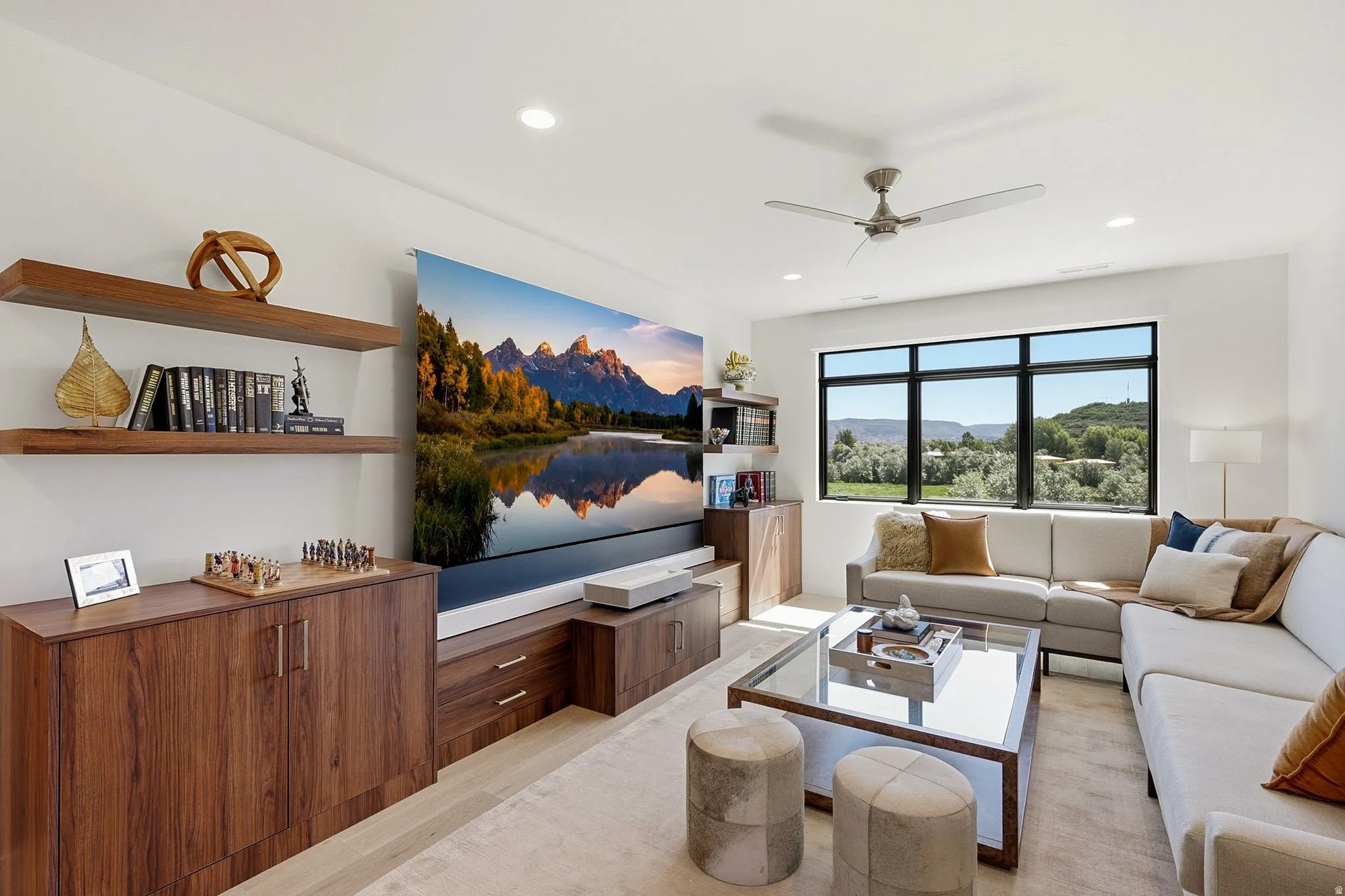 Living area featuring a large window, built-in shelving, wood-finish cabinetry, recessed lighting, and a ceiling fan