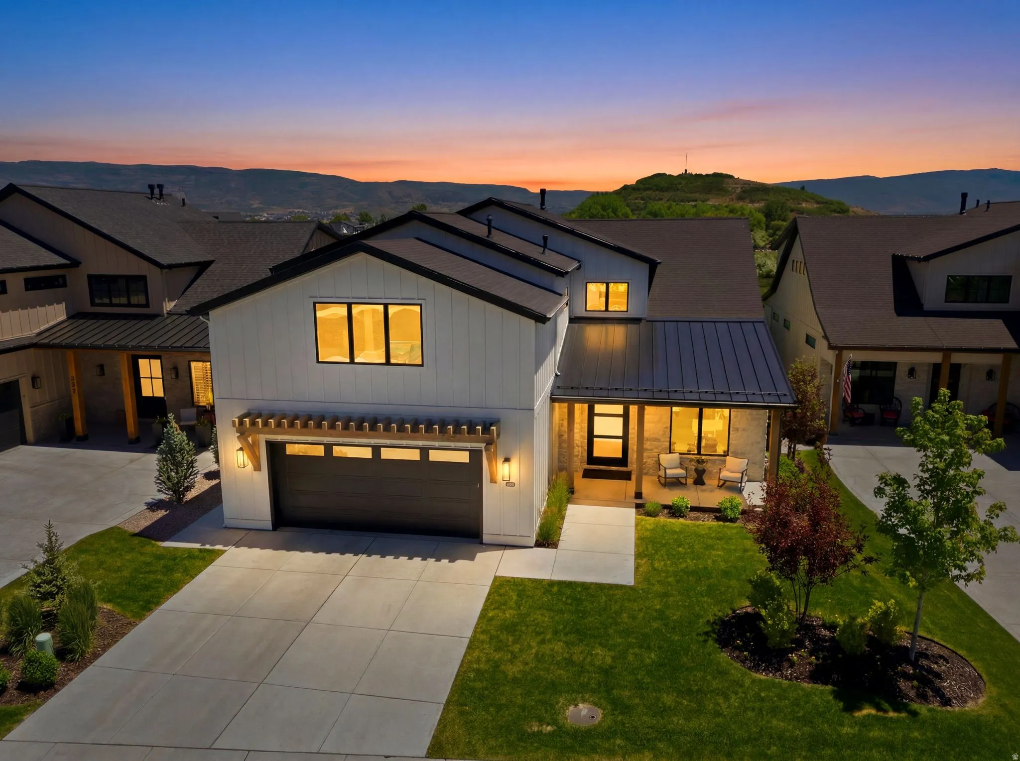 Modern farmhouse exterior featuring board and batten siding, stone accents, and a dark metal roof