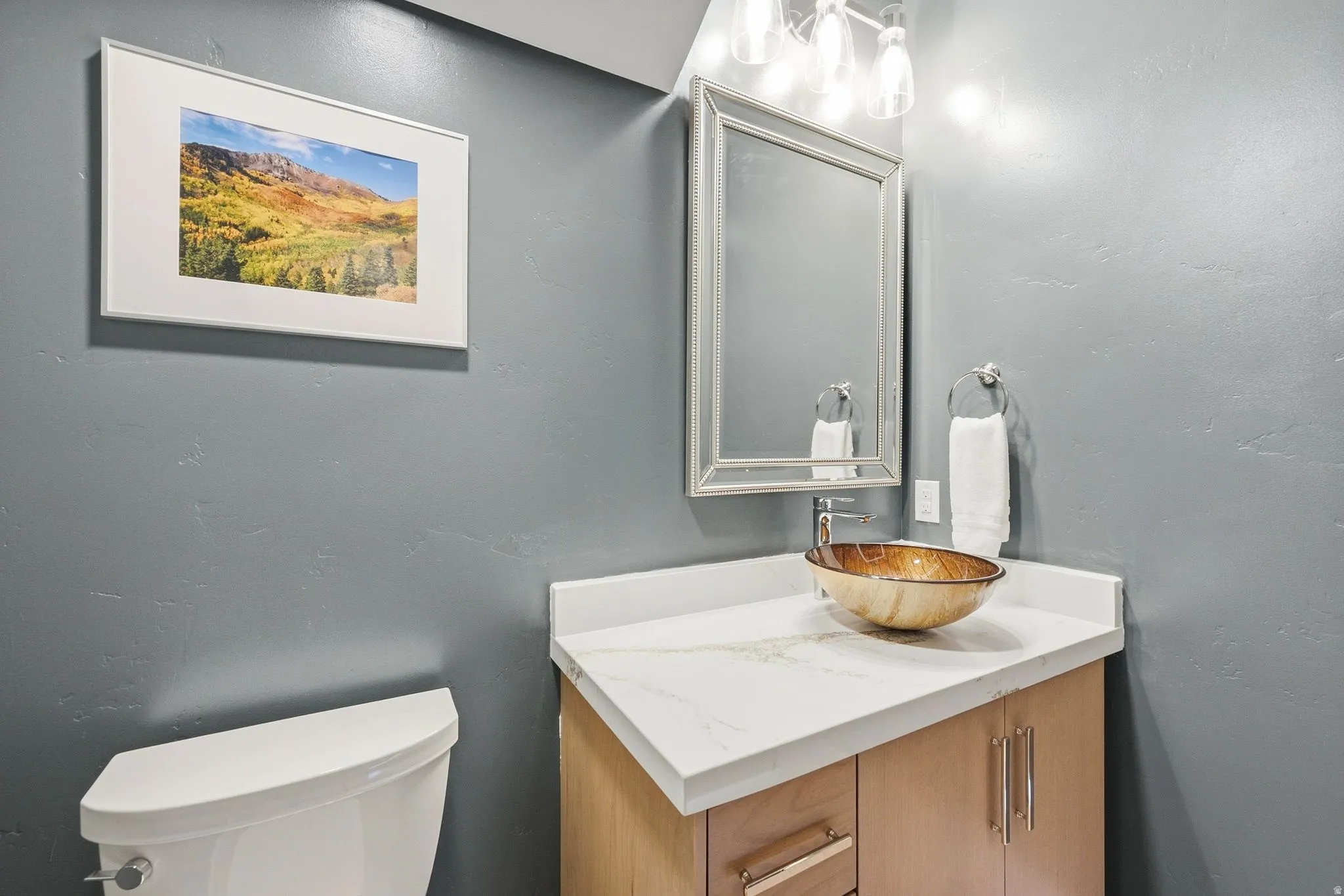 Vanity with a vessel sink, a light wood-finish base, and a light-toned countertop