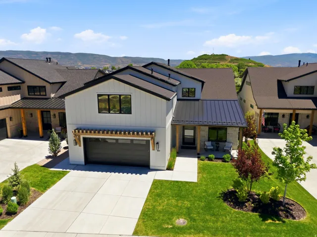 Modern farmhouse exterior featuring white vertical siding, black-framed windows, and a black metal roof accent
