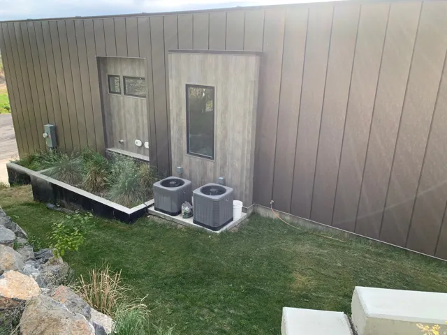 Vertical panel siding exterior with two recessed windows and a raised planting bed