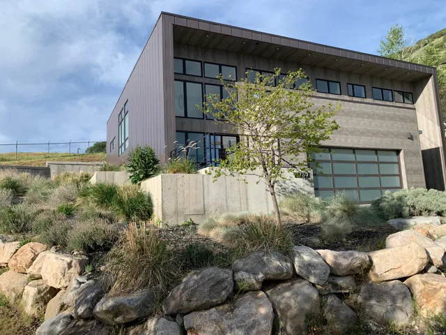 Modern architecture featuring multiple window styles, a glass-paneled garage door, and a brown metal roof
