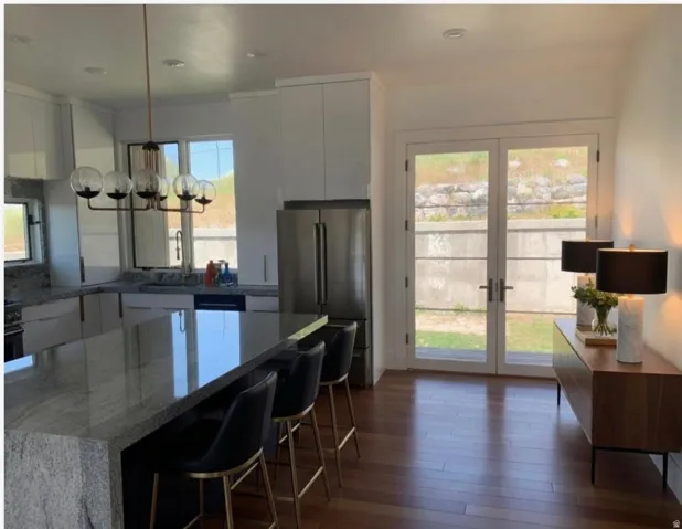 Modern kitchen featuring a large waterfall island with a polished countertop, sleek white cabinetry, and stainless steel appliances