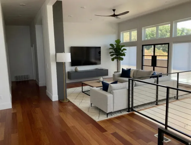Open-concept living area featuring hardwood flooring, a vaulted ceiling, and multiple transom windows