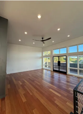 Expansive living area featuring warm wood-finish flooring, recessed ceiling lighting, and a modern ceiling fan
