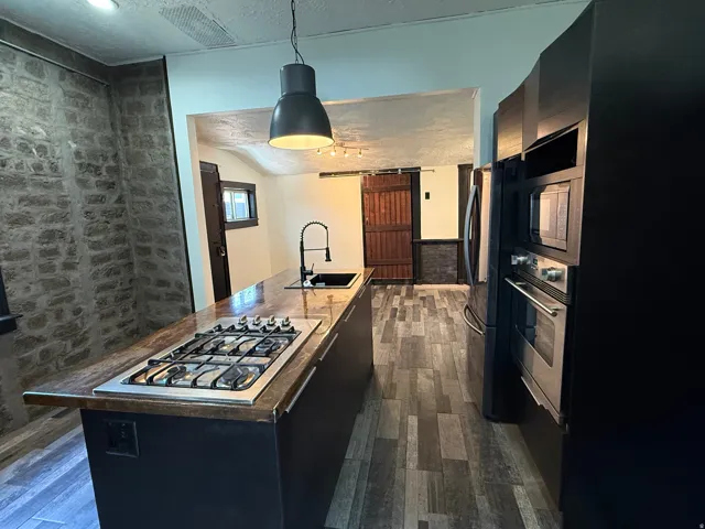 Modern kitchen featuring an island with a built-in gas range, integrated sink, and pendant lighting