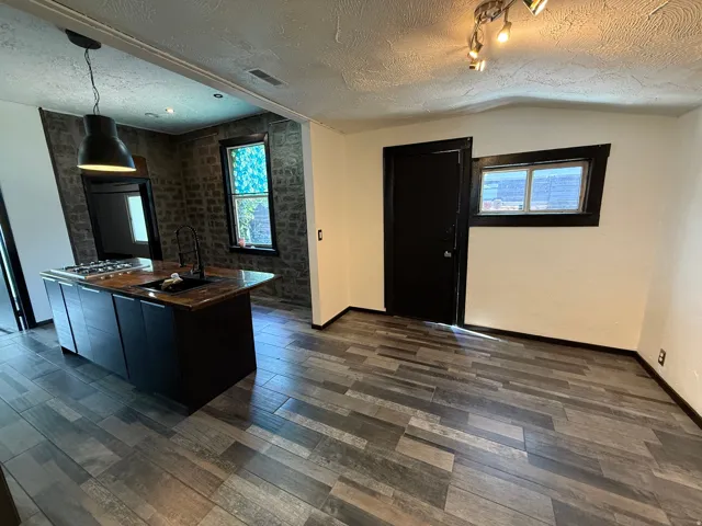 Kitchen island with integrated cooktop, undermount sink, and dark cabinetry