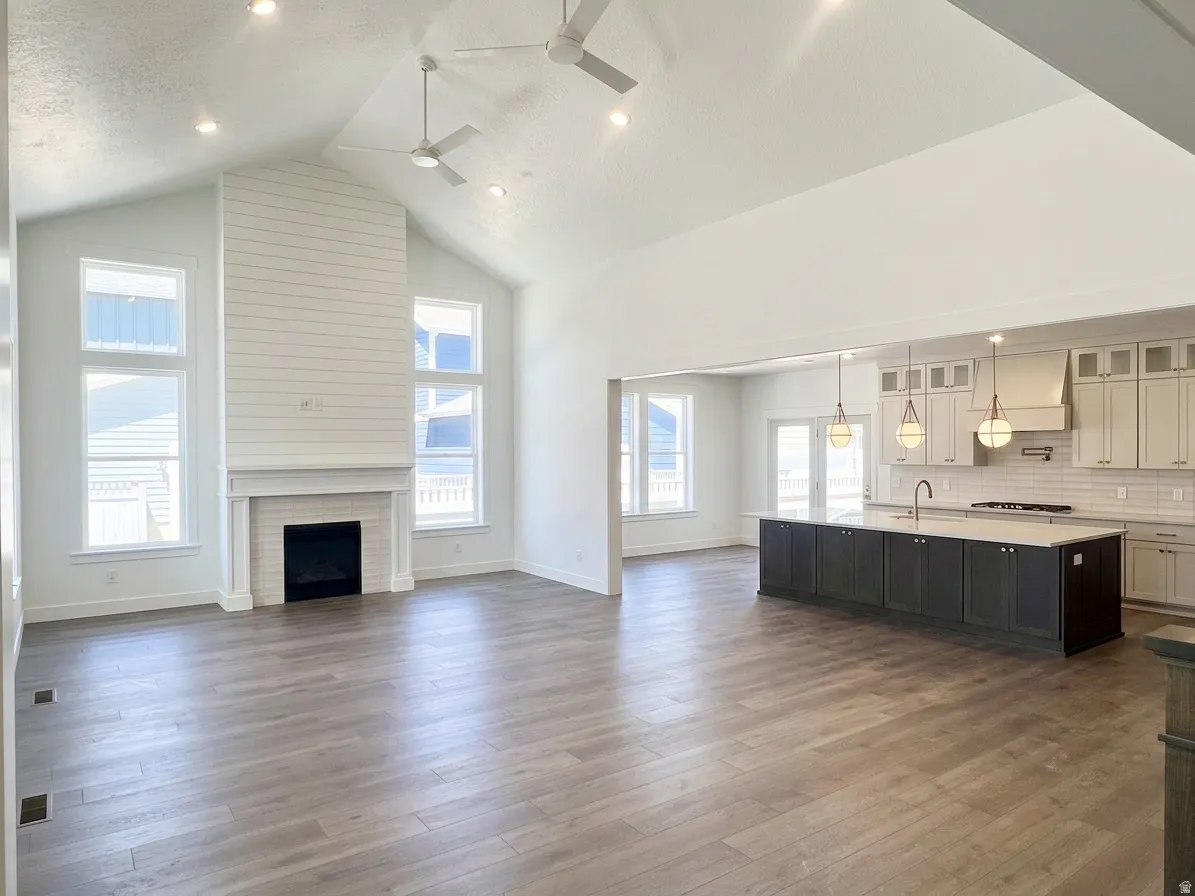 Spacious interior featuring vaulted ceilings with recessed lighting, a floor-to-ceiling shiplap fireplace, and wood-finish flooring