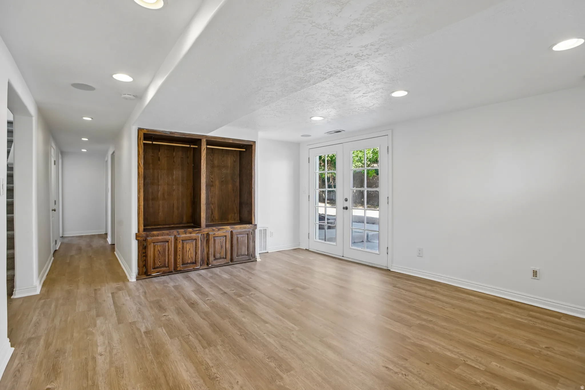 Spacious room featuring wood-finish flooring, recessed lighting, and a built-in wood storage unit