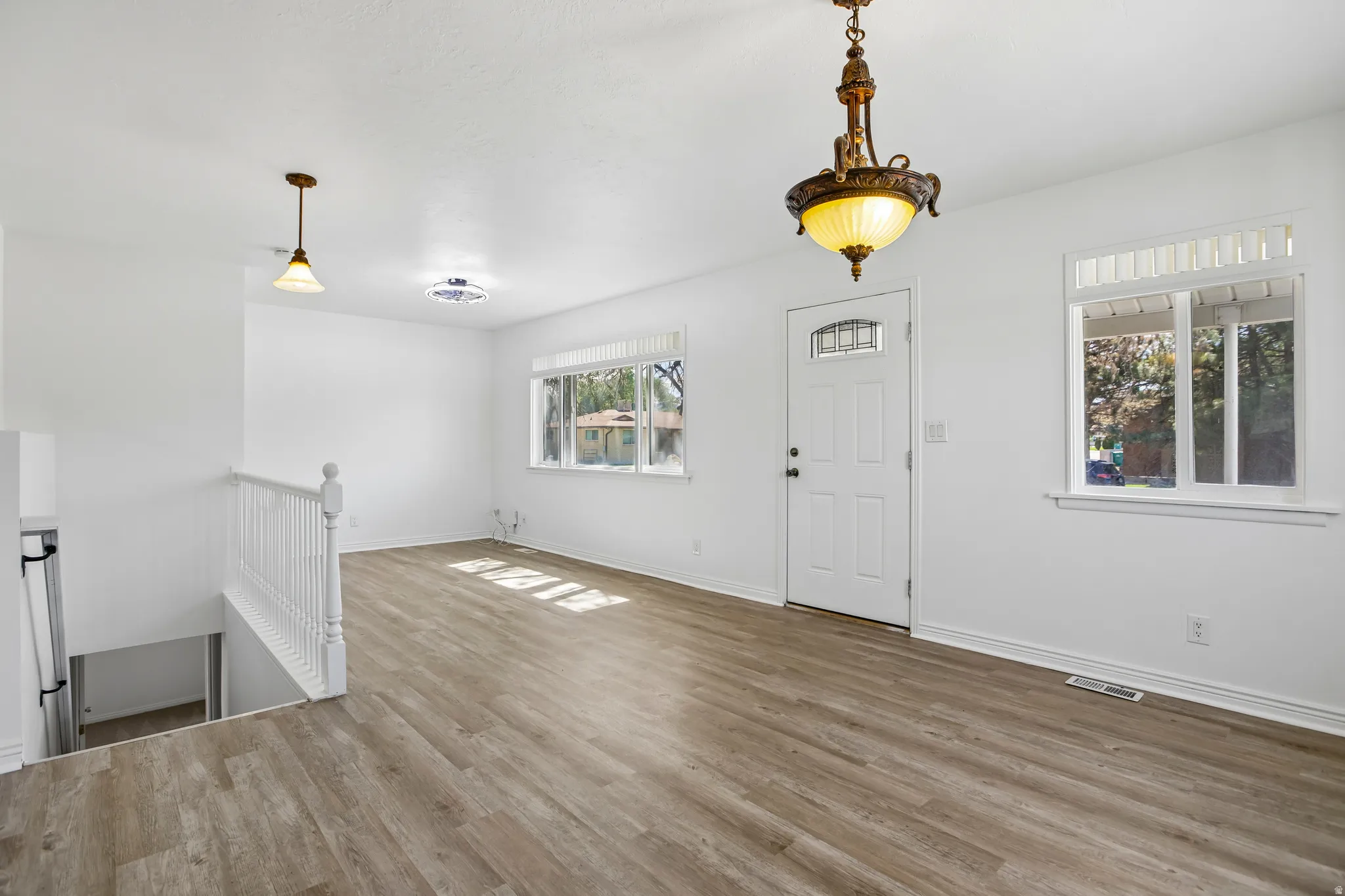 Open-concept living space with wood-finish flooring, white walls, and bright windows