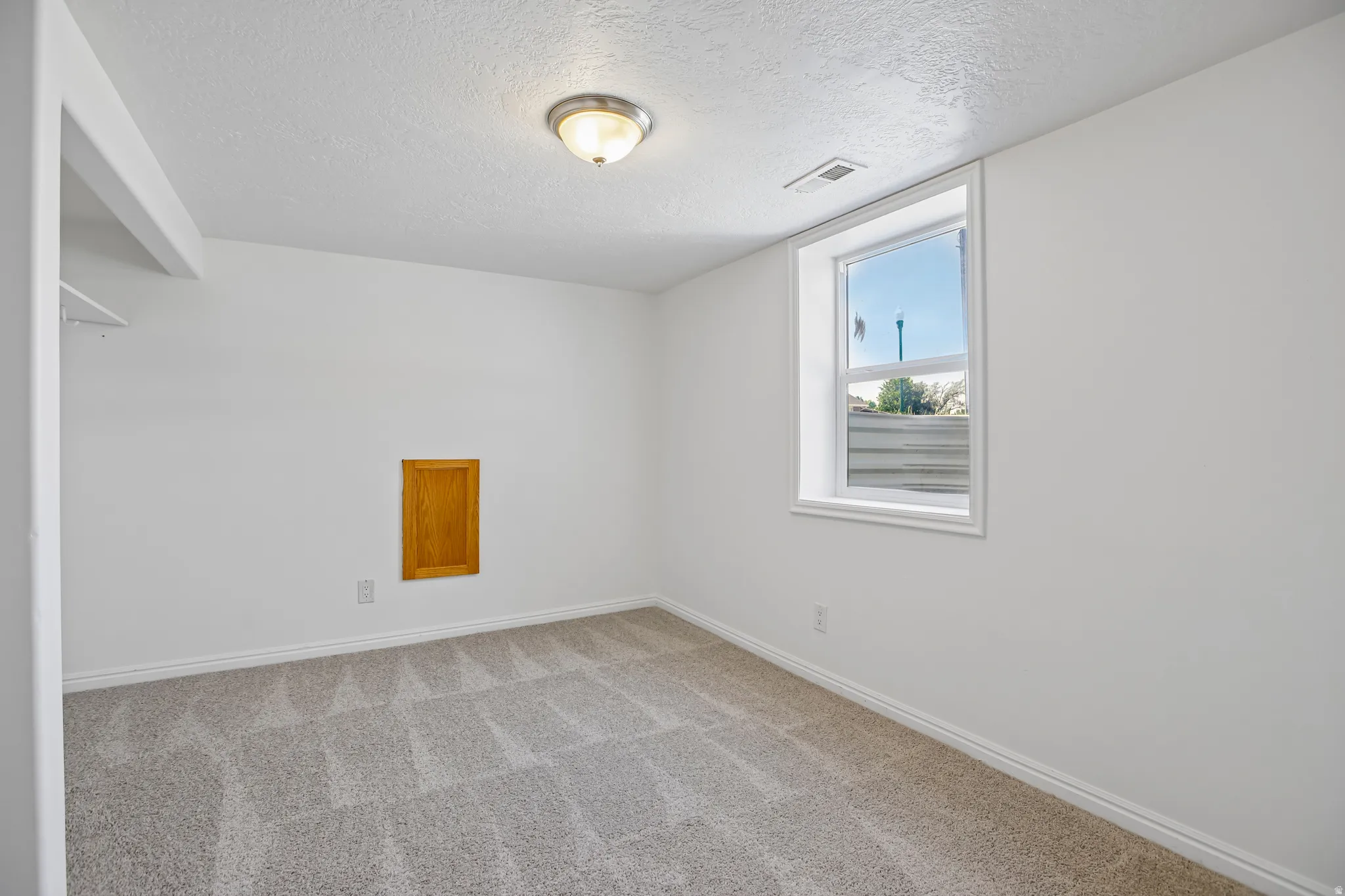 Interior room featuring neutral carpeting, white painted walls, and a single window with white trim