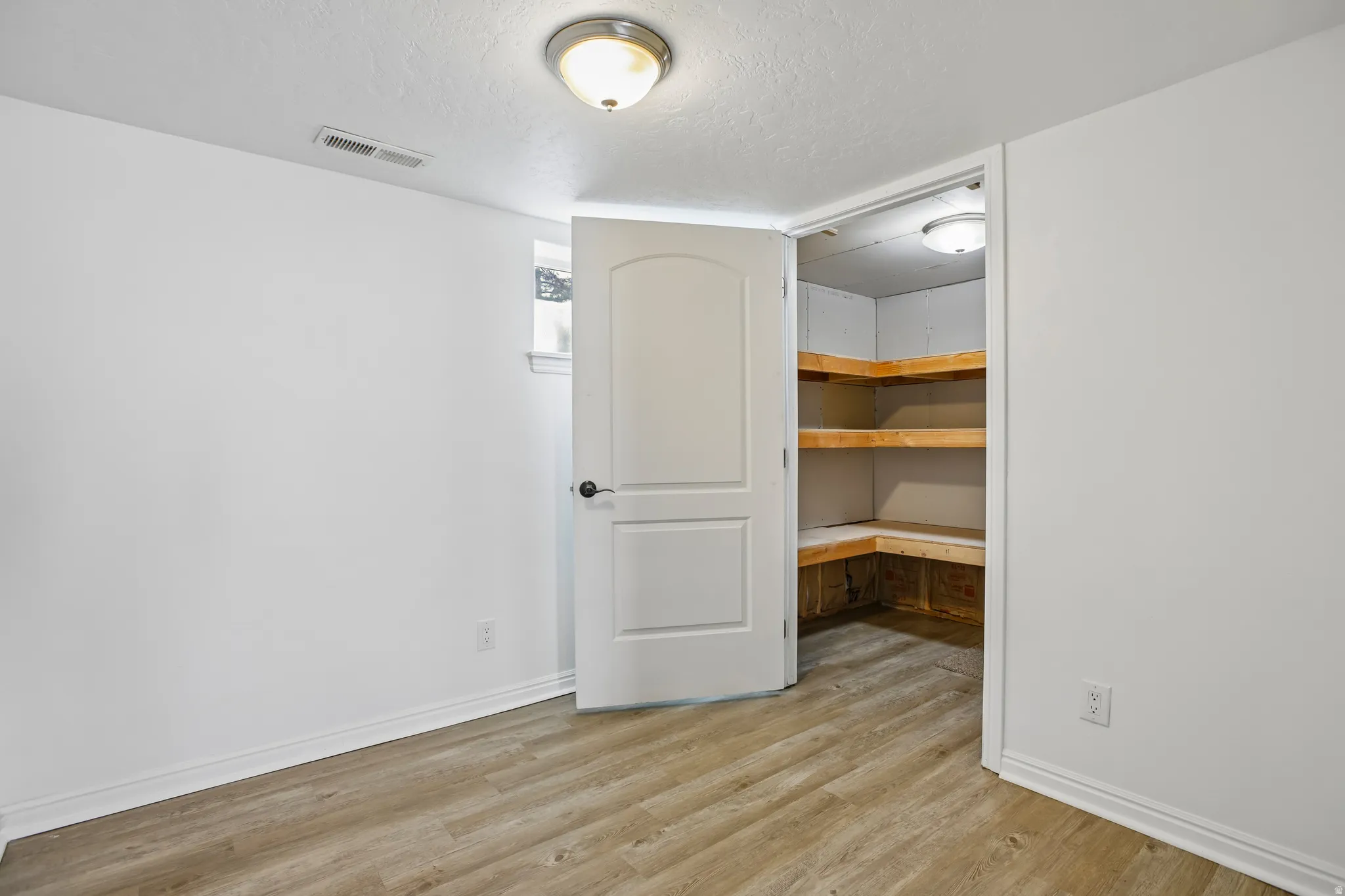 Room featuring wood-finish flooring, white baseboards, and a semi-flush mount ceiling light