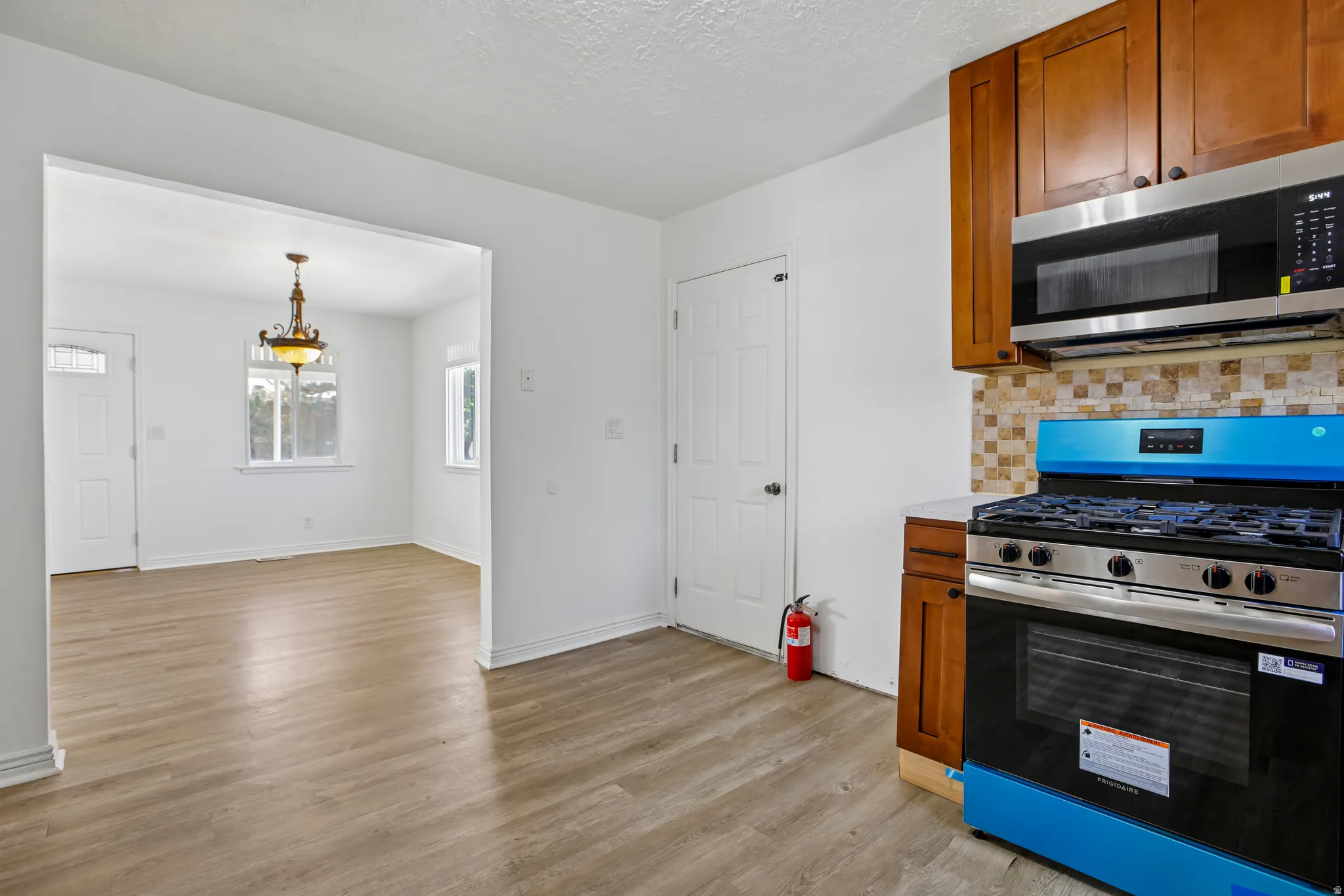 Kitchen featuring new stainless steel appliances, wood-finish cabinetry, and mosaic tile backsplash