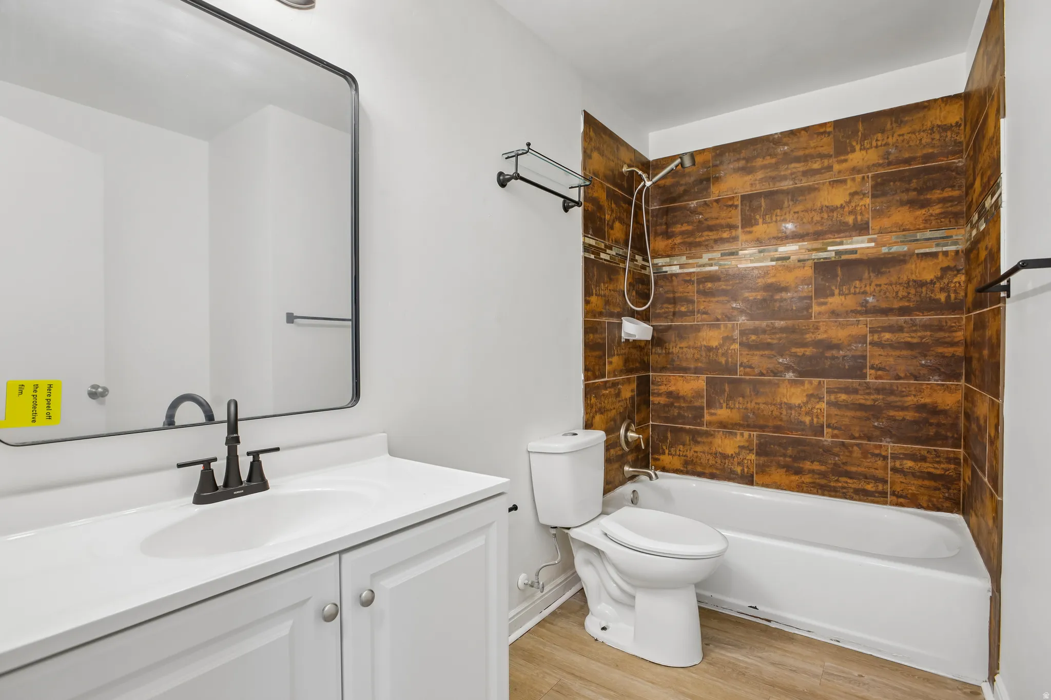 Bathroom featuring a white vanity with integrated sink, black-finish faucet, and a rectangular framed mirror
