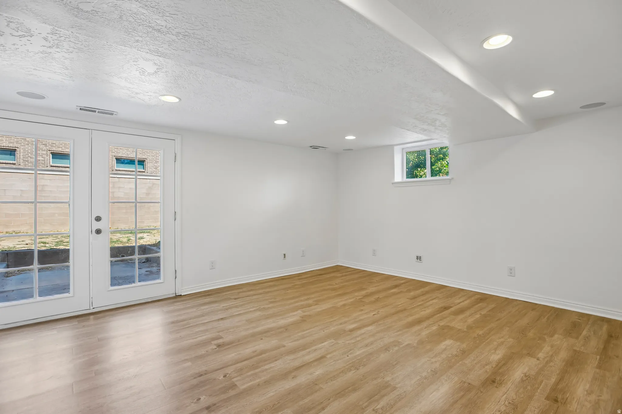 Spacious room featuring wood-finish flooring, white walls, and recessed lighting