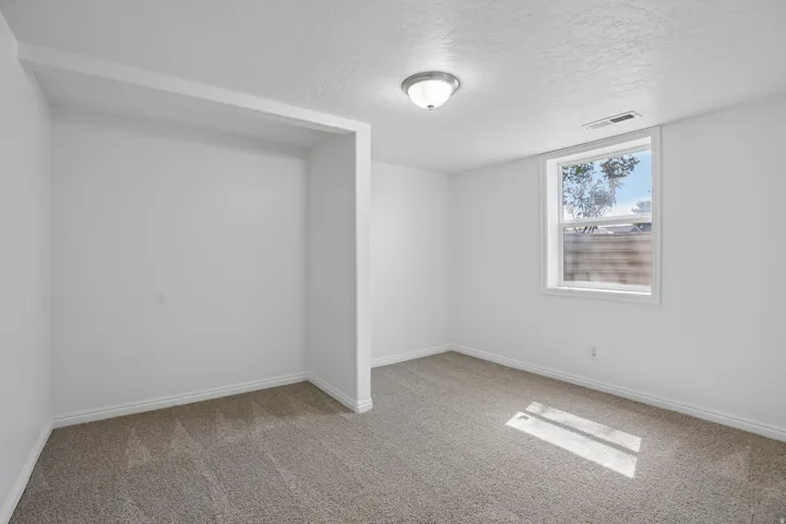 Carpeted room featuring a single window, white trim, and a built-in wall niche