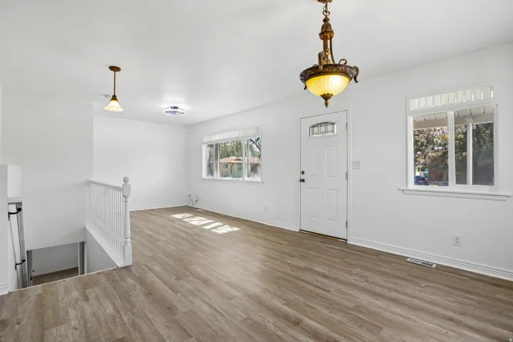 Open-concept living space with wood-finish flooring, white walls, and bright windows