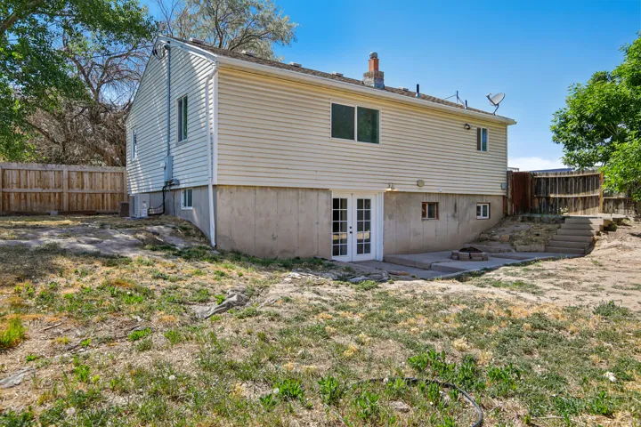 Rear exterior featuring light-colored siding, a concrete patio, and a wood privacy fence