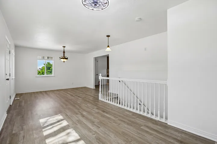 Spacious interior featuring wood-finish flooring, white painted walls, and a white baluster railing