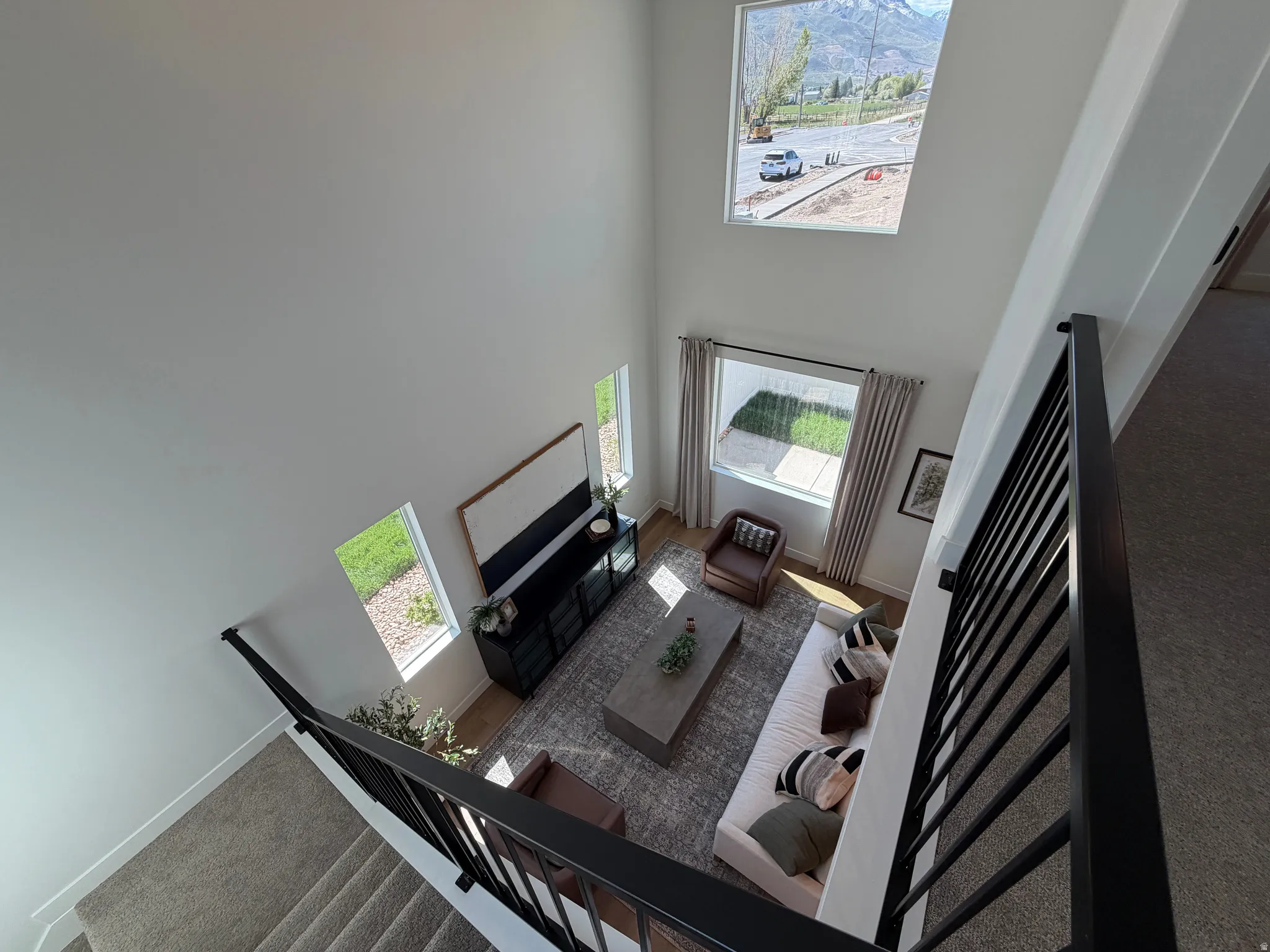 Two-story living room featuring a vaulted ceiling, multiple windows, and carpeted flooring