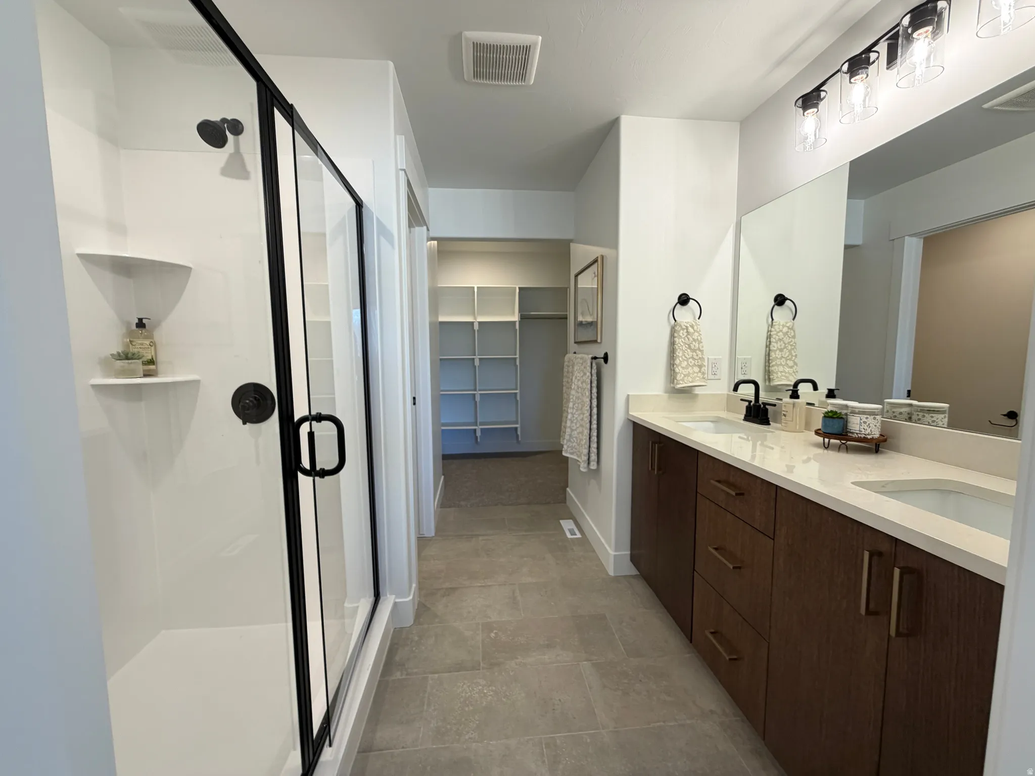 Modern bathroom featuring a double vanity with stone countertops and wood-finish cabinetry