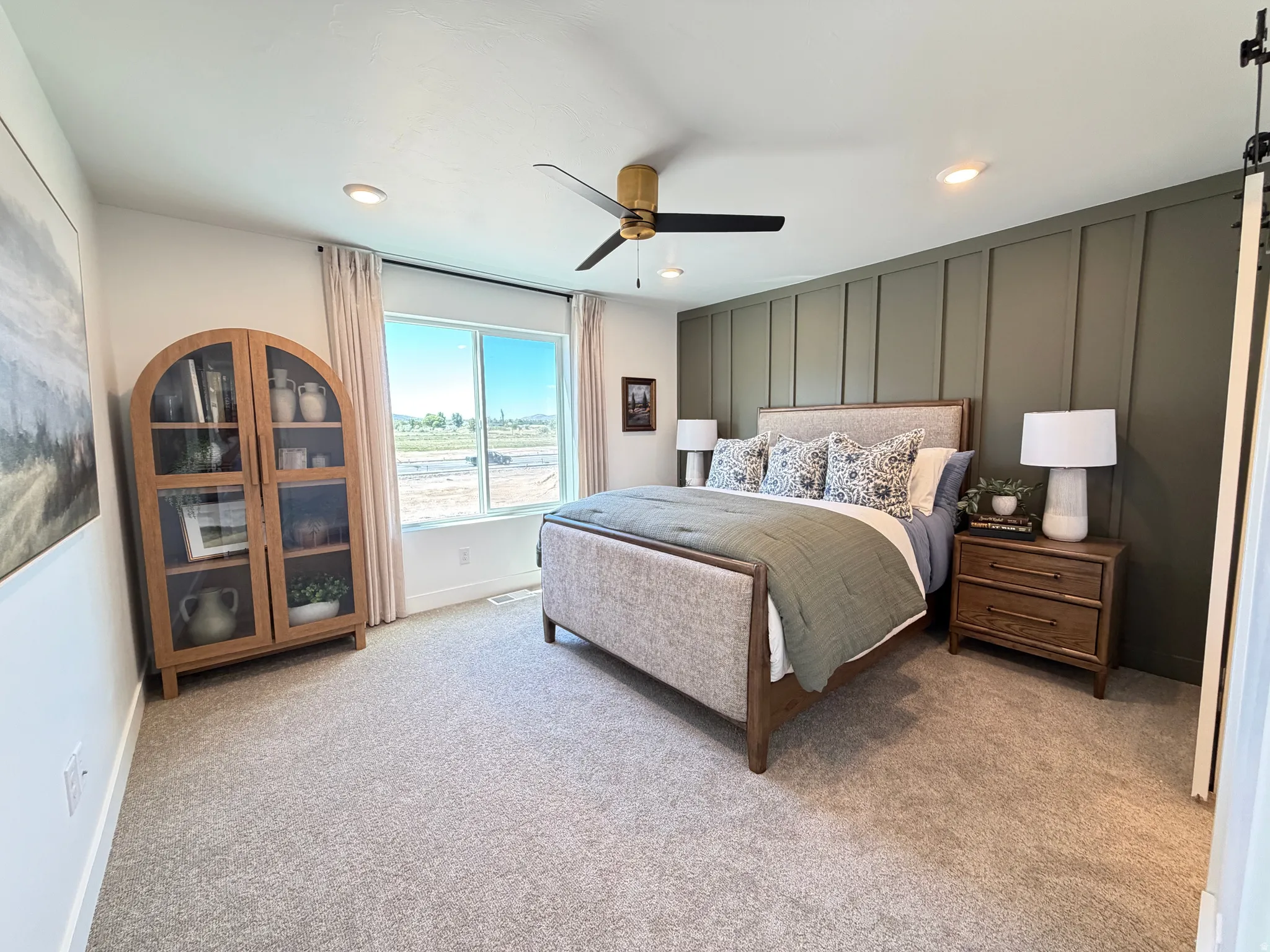 Bedroom featuring a green accent wall with vertical paneling, light gray carpeting, and a large window with white trim