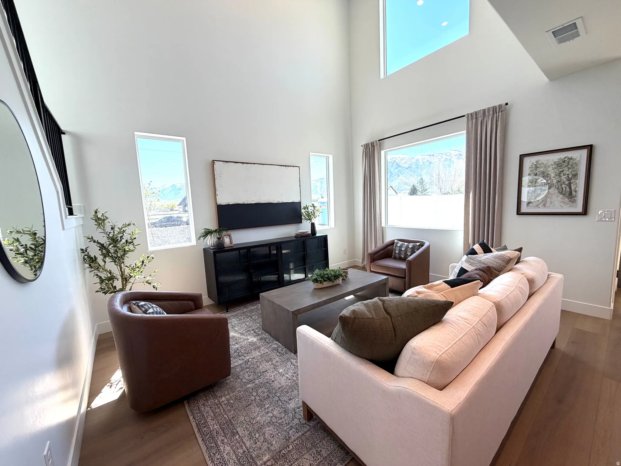 Living area featuring high ceilings, ample natural light from multiple windows, and wood-finish flooring