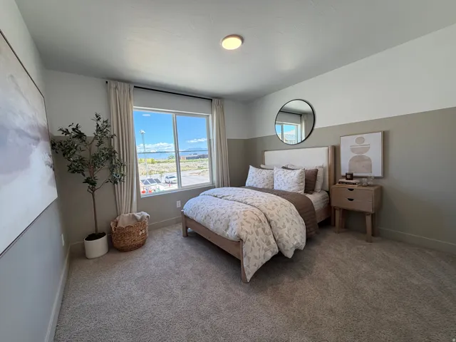 Bedroom featuring a window with exterior views, dual-tone painted walls, and plush carpeting