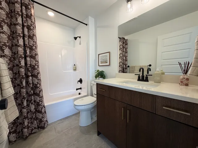Bathroom featuring a vanity with dark wood-finish cabinetry, a white countertop, and an integrated sink with matte black fixtures