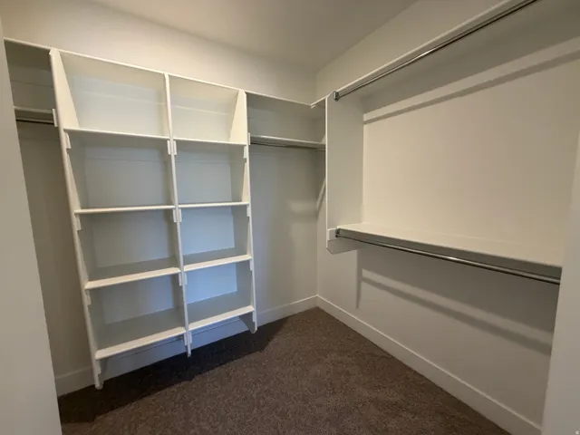 Walk-in closet featuring built-in shelving, white finish cabinetry, and dual chrome hanging rods