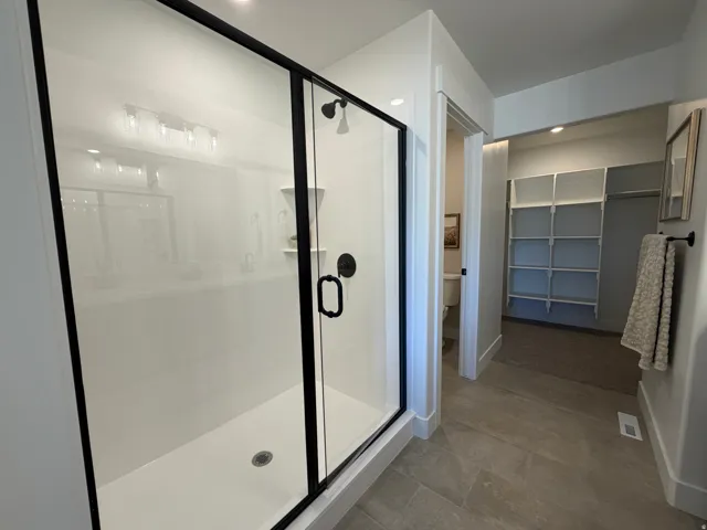 Shower enclosure featuring black-framed clear glass sliding doors and matte black fixtures
