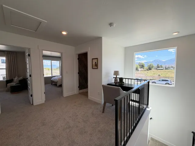 Upper-level landing featuring plush carpet, recessed lighting, and a window with mountain and field scenery