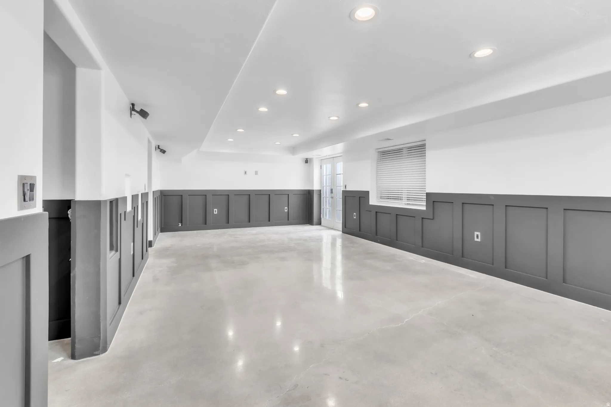 Spacious room featuring board and batten wainscoting, polished concrete flooring, recessed lighting, and a window with blinds